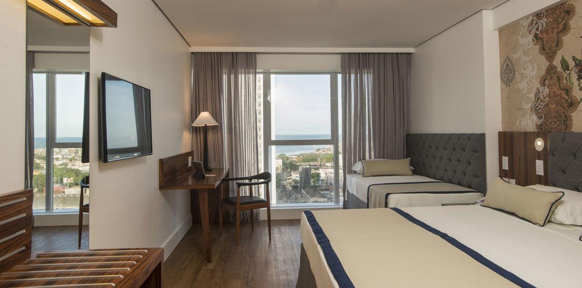 Hotel Luzeiros Recife Exterior foto The photo shows a modern hotel room. It features two beds with a simple design, one larger and one smaller. There's a large window with sheer curtains, allowing natural light to fill the space and offering a view of the outside. A wooden desk and cha