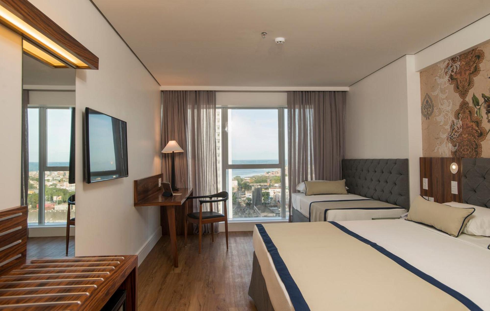 Hotel Luzeiros Recife Exterior foto The photo shows a hotel room that features a modern and comfortable design. There are two beds: one larger bed and a smaller twin bed. The room has large windows with curtains that allow natural light to enter, offering a view of the outside, possibl
